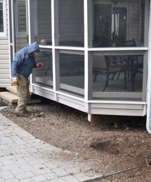 A-AAA Tree Service SP7015 stump grinder reducing a stump to mulch beside a screened porch, leaving a clean flat surface